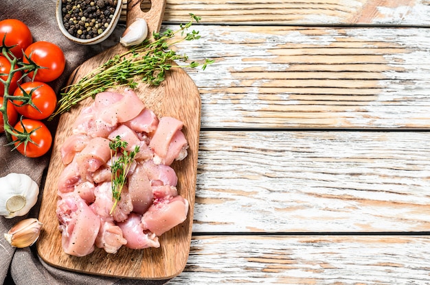 Raw chicken meat fillet cut into cubes on cutting board