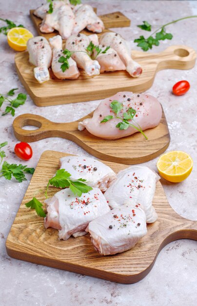 Foto filetto di carne di pollo crudo, coscia, ali e zampe con erbe, spezie, limone e aglio. vista dall'alto