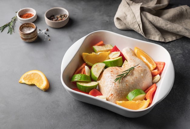 Raw chicken meat with vegetables oranges and spices in pan on kitchen counter healthy diet