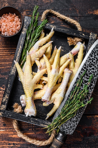 Raw Chicken paws feets on butcher chopping board with knife.