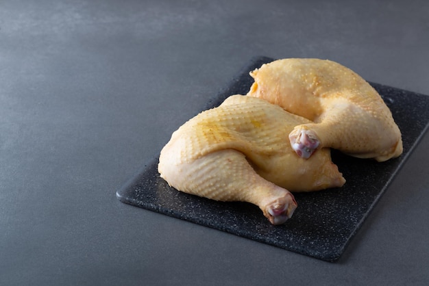 Raw chicken quarters legs on board on gray background