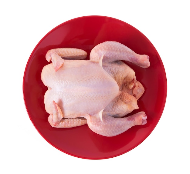 Foto pollo crudo su un piatto rosso isolato su sfondo bianco