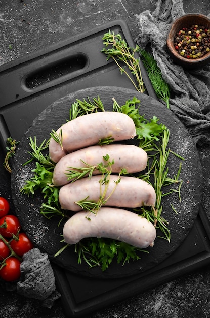 Raw Chicken sausages with cheese on a black stone plate Top view Old background rustic style