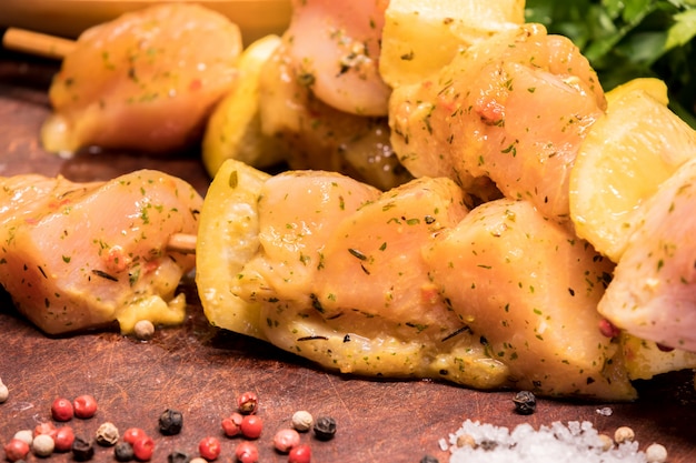 Raw chicken skewers marinated with lemon on a wooden board