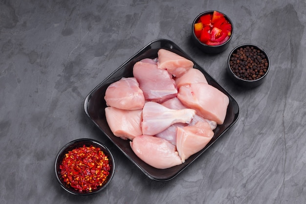 Raw chicken tender curry cut without skin arranged on black plate