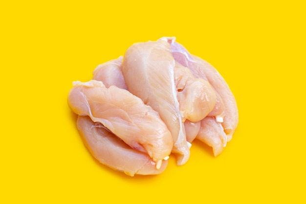 Raw chicken tenders on yellow background