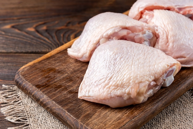 Raw chicken thigh on wooden table