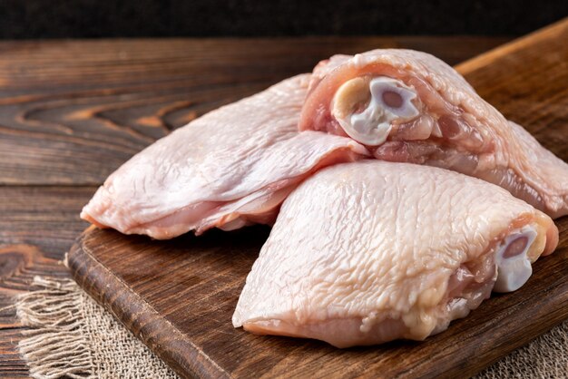 Raw chicken thigh on wooden table