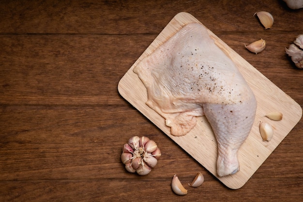 Raw chicken thighs and garlic pepper on a wooden table