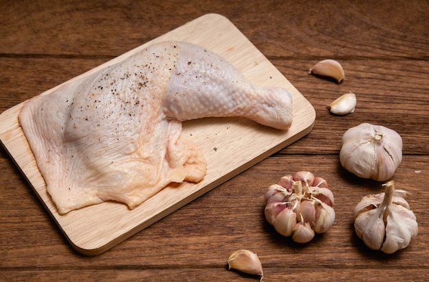 Raw chicken thighs and garlic pepper on a wooden table