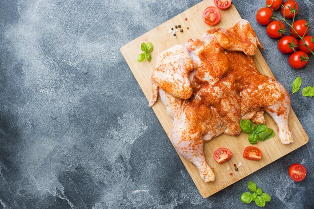 Tabacco di pollo crudo su una tavola di legno con spezie e verdure copia spazio