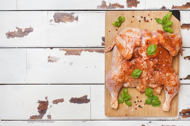 Raw chicken tobacco on a wooden Board with spices and vegetables Copy space