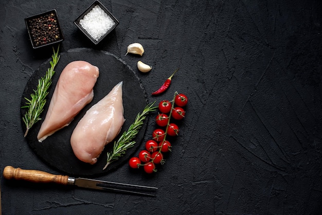 Raw chicken and vegetables on a black background