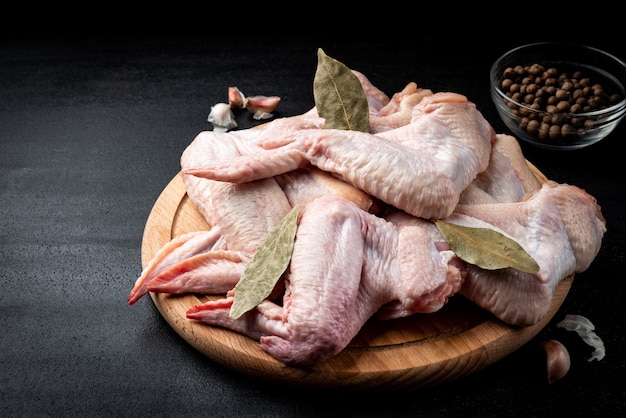 Raw chicken wings on black background.