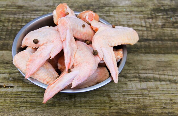 Raw chicken wings in bowl on the rustic wooden table