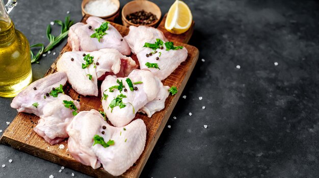 raw chicken wings on a cutting board with spices on a stone background 