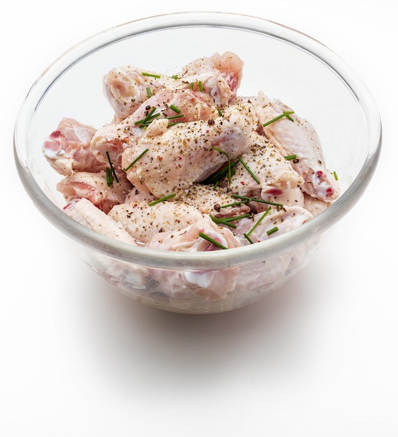소금, 후추, 향신료 흰색 배경에 고립 된 그릇에 절인 원시 닭 날개.