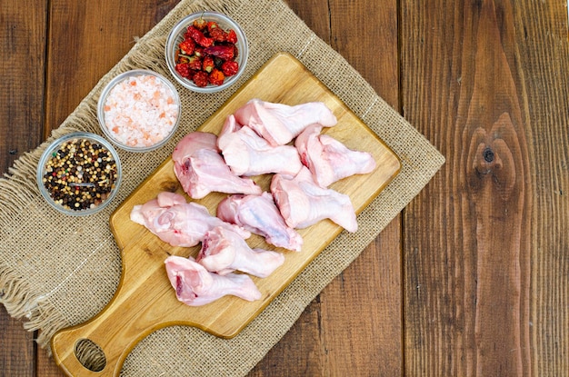 Photo raw chicken wings with bone and skin on wooden cutting board. studio photo