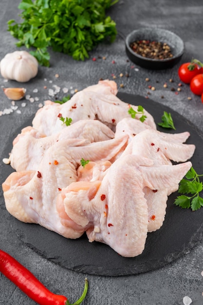 Raw chicken wings with fresh herbs spices for cooking on concrete background Top view copy space