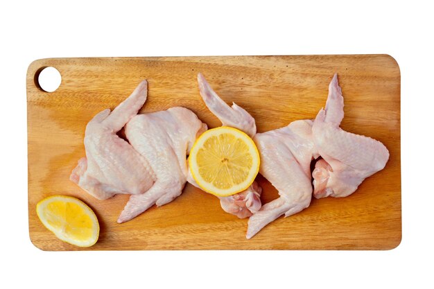 Raw chicken wings with lemon slices on cutting board isolated on white background with clipping path