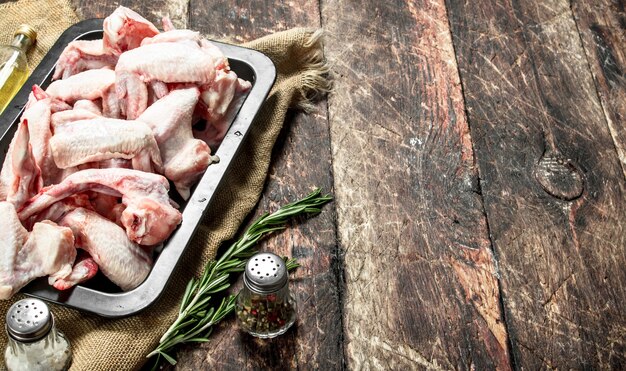 Raw chicken wings with spices and herbs on a wooden table.