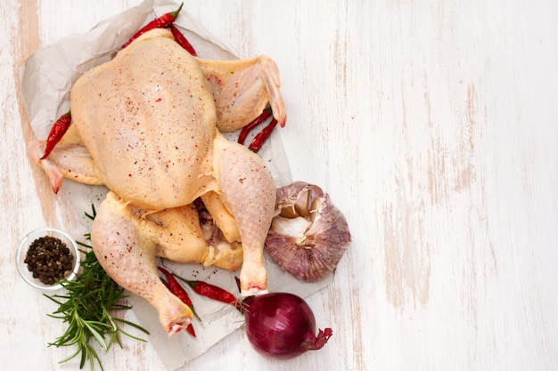 Raw chicken with herbs and garlic on wooden surface