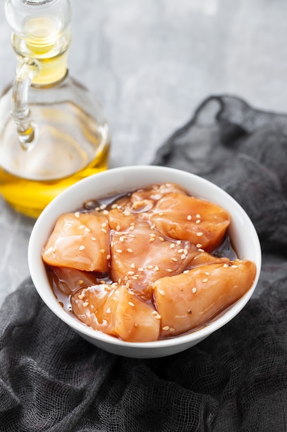 Raw chicken with sauce and sesame in white bowl