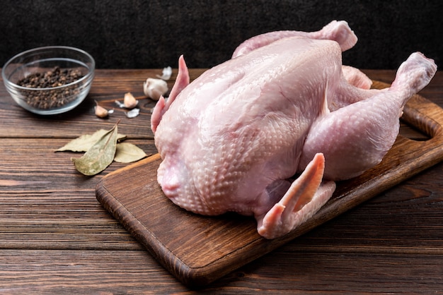 Raw chicken on wooden background with spices.