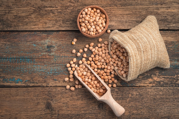 Raw chickpeas are poured out of a bag on a wooden table. Top view, copy space. Healthy food.