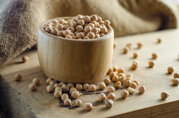 Raw chickpeas in a bowl on a wooden board