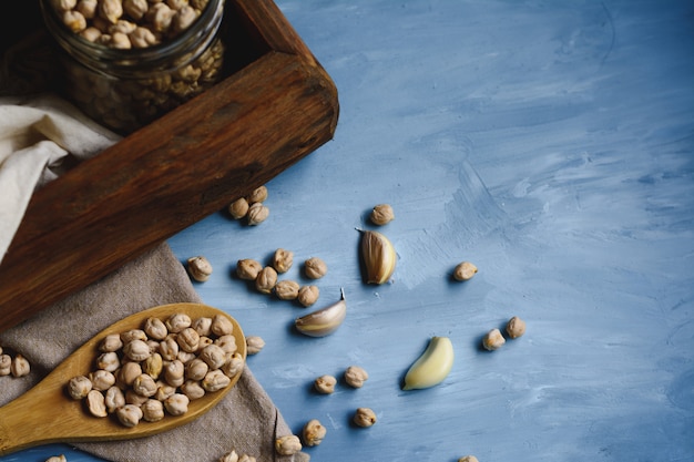 Raw chickpeas in a glass jar and wood spoon.