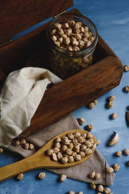 Raw chickpeas in a glass jar and wood spoon.