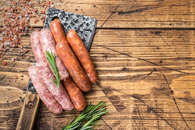 Raw Chorizo and Bratwurst sausages on a butcher meat cleaver. wooden background. Top View. Copy space.