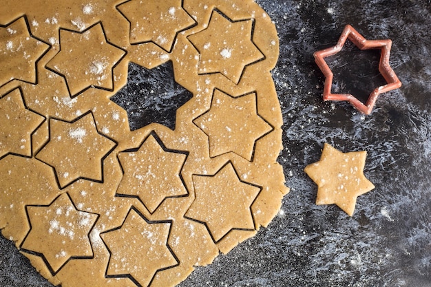 Raw christmas homemade gingerbread dough rolled out on dark table