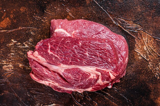 Raw Chuck eye roll beef steak on butcher table. Dark table. Top view.