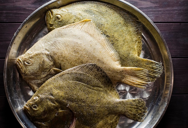 生のきれいにされたヒラメの丸ごとの魚は調理の準備ができています