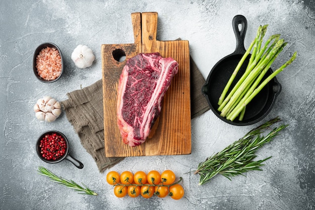 Raw club steak with ingredients set, on gray stone