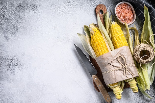 Raw corn on cobs on rustic table.