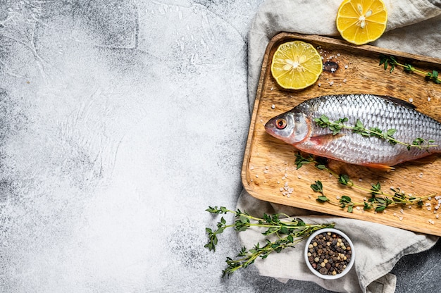 Raw crucian carp on a wooden tray. River organic fish. Top view. Copyspace background.