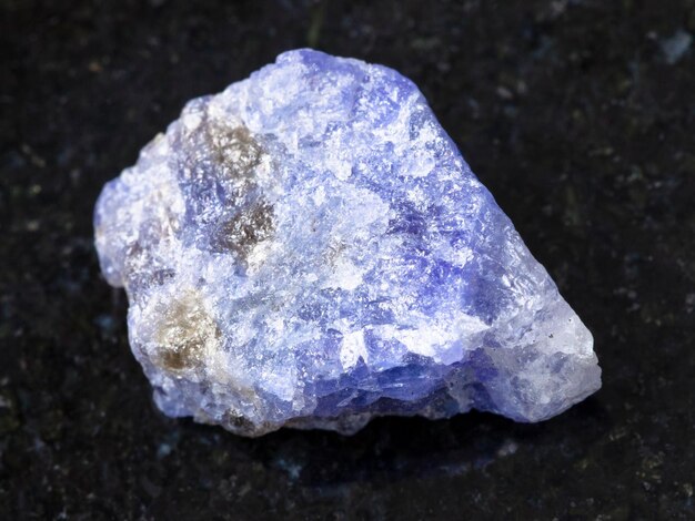 Raw crystal of Tanzanite gemstone on dark