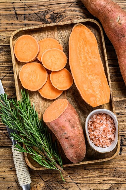 Raw cut yam Sweet potato. wooden background. Top view.