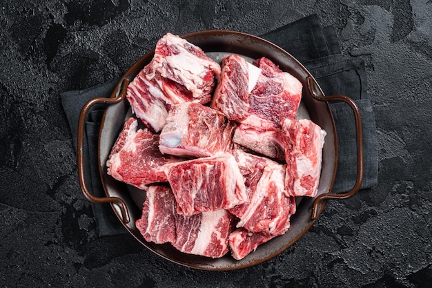 Carne marmorizzata di manzo e agnello cruda a dadini in vassoio in acciaio da cucina sfondo nero vista dall'alto