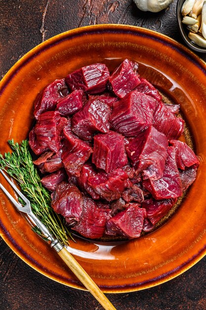 Raw diced deer steak for a venison goulash. Dark table. Top view.