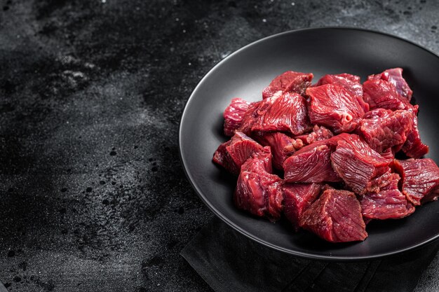 Raw Diced game meat of wild venison dear Black background Top view Copy space