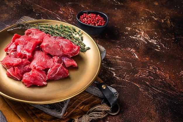 Raw diced lamb mutton meat with thyme Dark background Top view Copy space