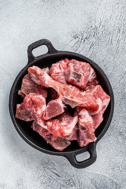 Raw diced meat cubes with bone in a pan. white table. Top View.