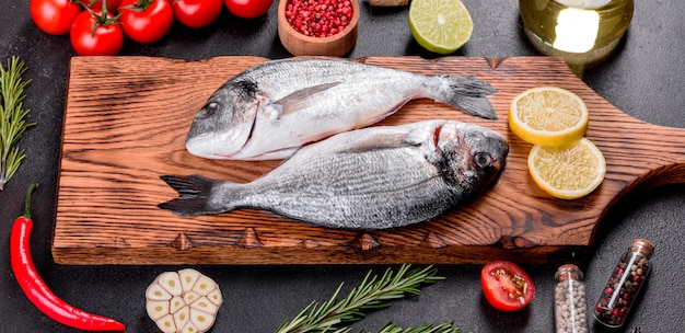 Raw dorado fish with spices cooking on cutting board. Fresh fish dorado. Dorado and ingredients for cooking on a table