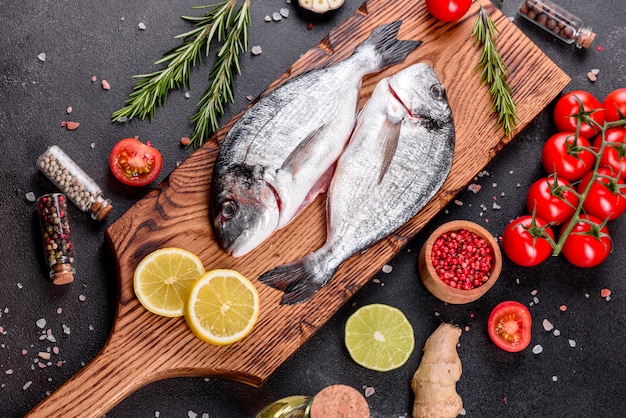 まな板の上で調理するスパイスと生のドラド魚。新鮮な魚のドラド。ドラドとテーブルで調理するための食材