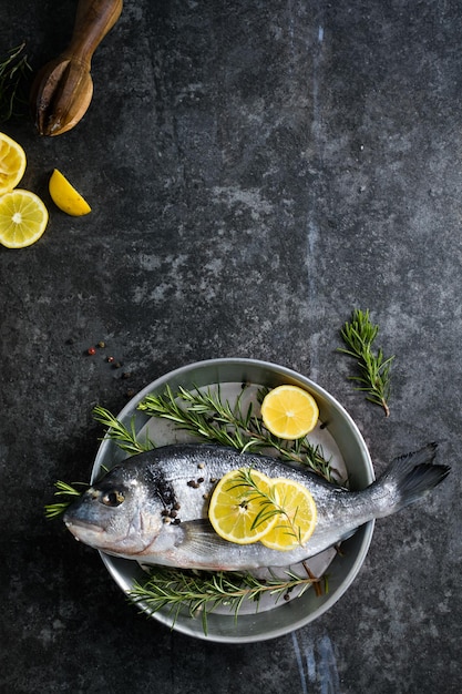 Pesce crudo di dorado con spezie dorado e ingredienti per cucinare su un tavolo