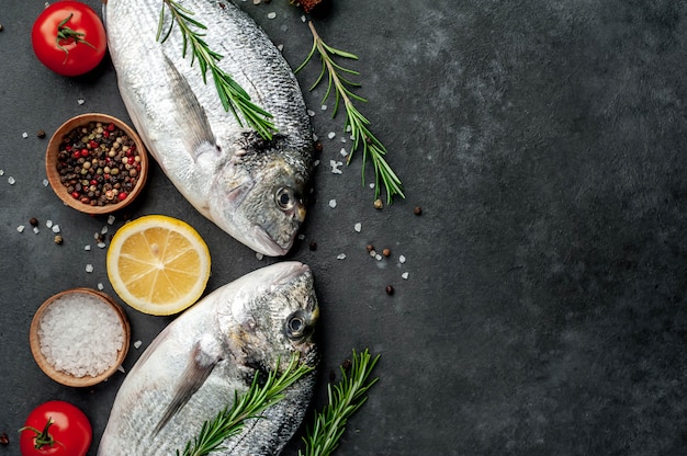 Raw dorado fish with spices and ingredients tomato, razmorin, sunflower oil, lemon on a stone background with copy space for your text